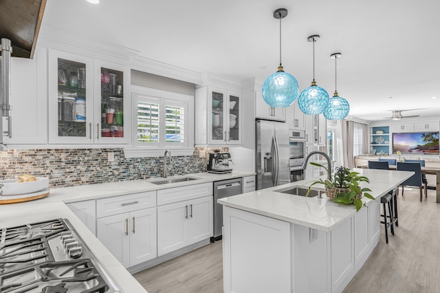 kitchen with sink, white cabinetry, stainless steel appliances, and an island with sink