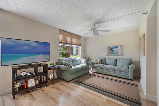 living room featuring a textured ceiling, light hardwood / wood-style flooring, and ceiling fan