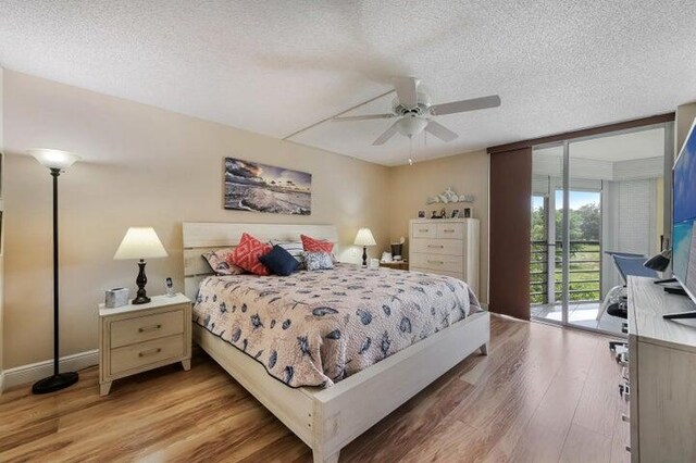 bedroom featuring expansive windows, a textured ceiling, access to outside, ceiling fan, and hardwood / wood-style floors