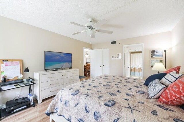 bedroom featuring a textured ceiling, light wood-type flooring, ceiling fan, and connected bathroom