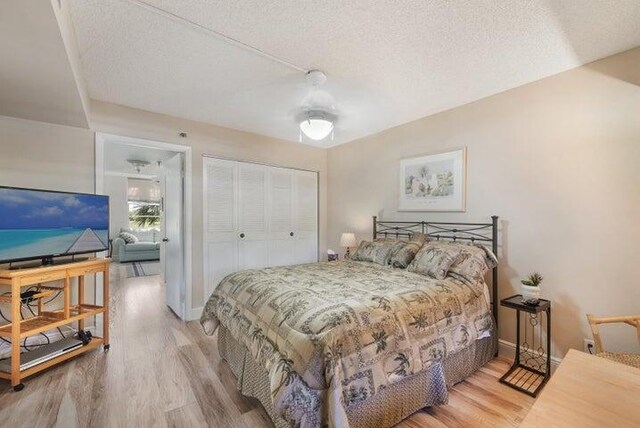 bedroom with ceiling fan, a closet, wood-type flooring, and a textured ceiling