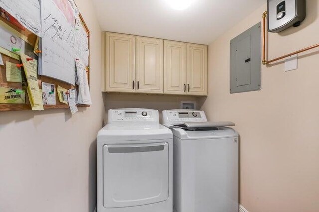 clothes washing area featuring electric panel, cabinets, and washing machine and dryer