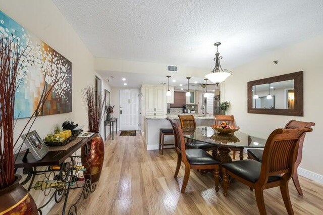 dining room with a textured ceiling and light wood-type flooring