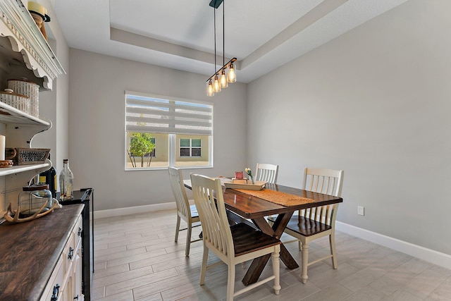 dining space featuring a tray ceiling and light hardwood / wood-style flooring