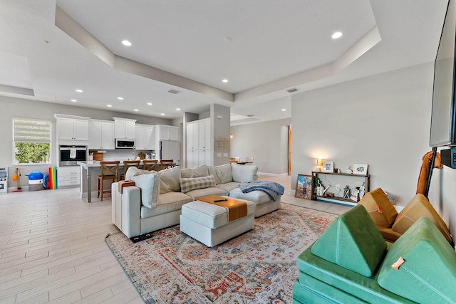 living room with a raised ceiling and light hardwood / wood-style flooring