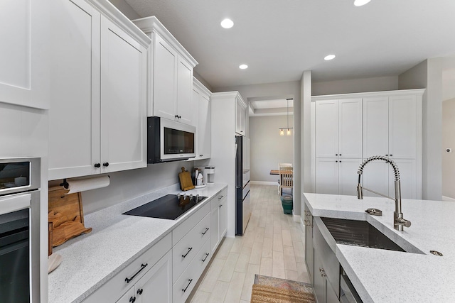 kitchen featuring light stone countertops, stainless steel appliances, sink, light hardwood / wood-style floors, and white cabinetry