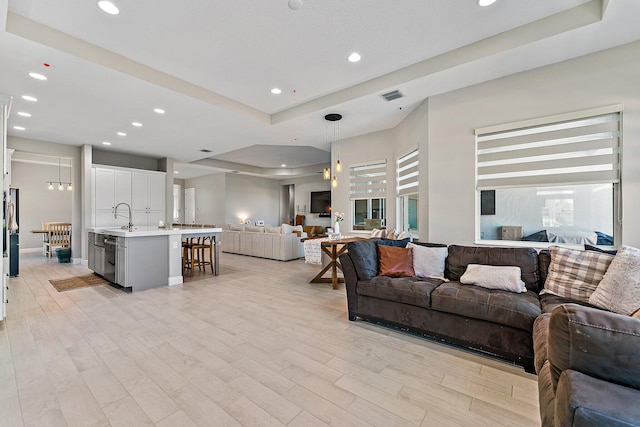 living room featuring a tray ceiling and light hardwood / wood-style flooring