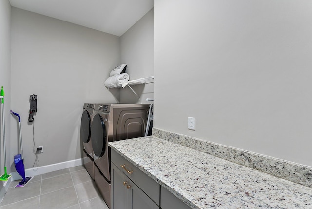 clothes washing area featuring cabinets, washing machine and dryer, and light tile patterned flooring