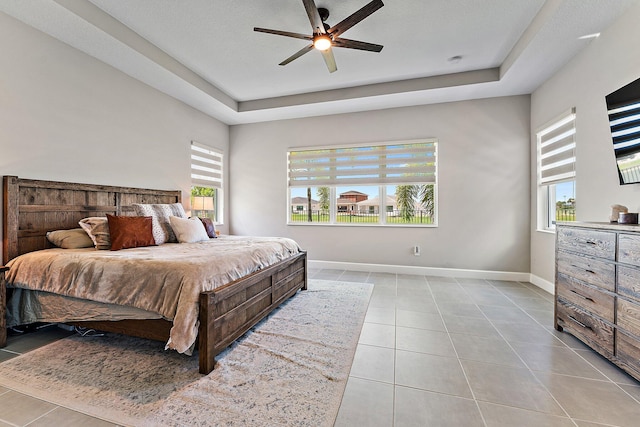 bedroom with ceiling fan, light tile patterned flooring, a raised ceiling, and a textured ceiling