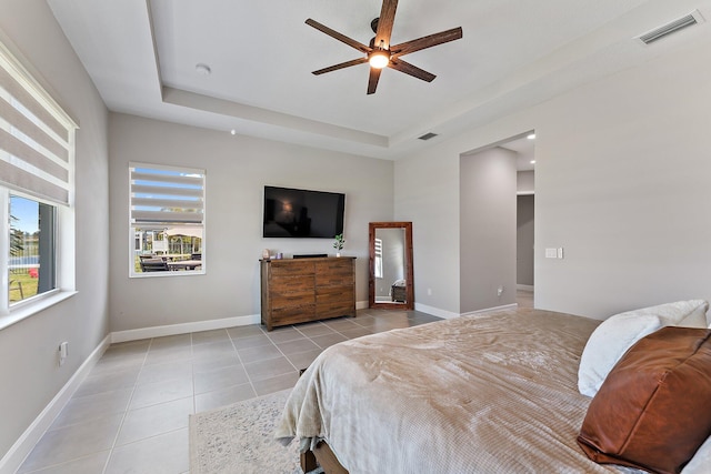 bedroom featuring a tray ceiling, ceiling fan, and light tile patterned floors