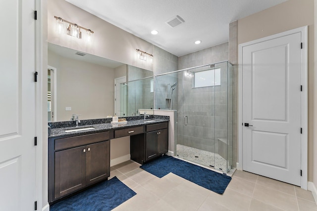 bathroom with tile patterned flooring, vanity, a textured ceiling, and walk in shower