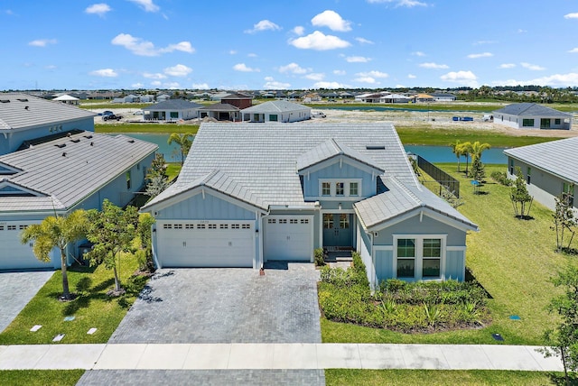 view of front facade featuring a front lawn, a water view, and a garage