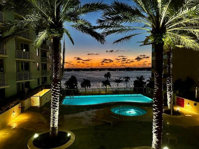 pool at dusk featuring a water view