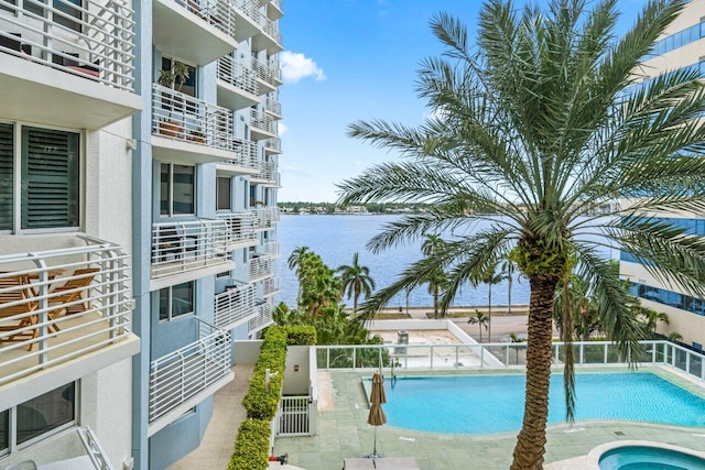 view of pool with a water view, a community hot tub, and a patio