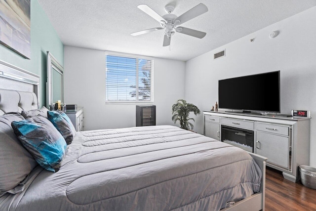 bedroom with a textured ceiling, ceiling fan, and dark hardwood / wood-style floors