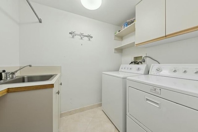 washroom with cabinets, light tile patterned floors, washing machine and dryer, and sink