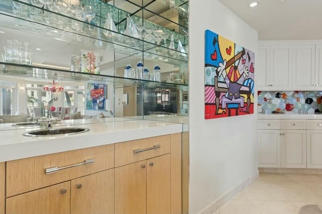 bar with white cabinets, light tile patterned floors, backsplash, and sink