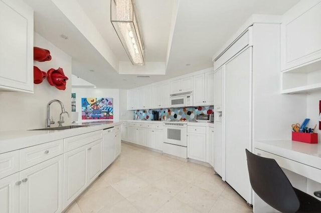 kitchen featuring tasteful backsplash, white cabinetry, sink, and white appliances