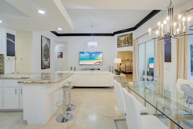 kitchen featuring white cabinetry, a kitchen breakfast bar, light stone counters, decorative light fixtures, and ornamental molding