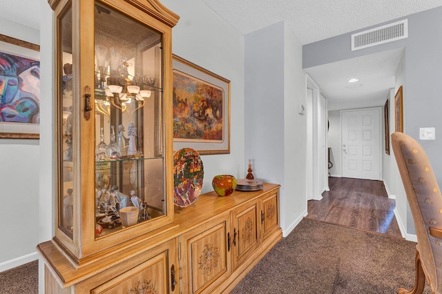 corridor with dark hardwood / wood-style flooring and a textured ceiling