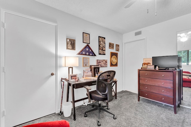 carpeted home office with ceiling fan and a textured ceiling