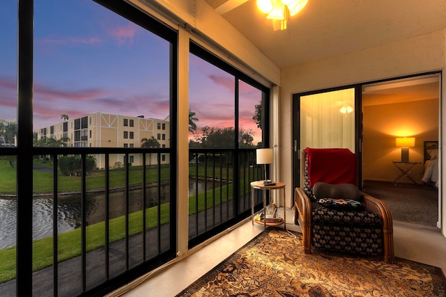 sunroom featuring ceiling fan and a water view