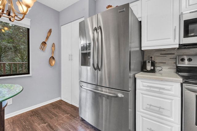 kitchen with appliances with stainless steel finishes, tasteful backsplash, an inviting chandelier, dark hardwood / wood-style floors, and white cabinetry