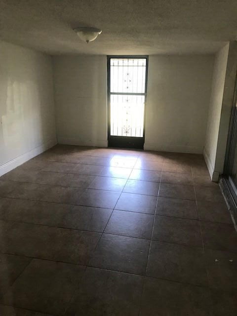 tiled spare room with a textured ceiling