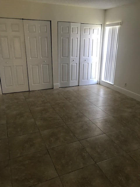 unfurnished bedroom featuring dark tile patterned floors and two closets