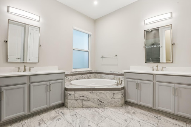 bathroom featuring a relaxing tiled tub and vanity