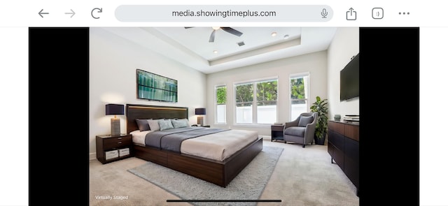 bedroom featuring ceiling fan, light carpet, and a tray ceiling