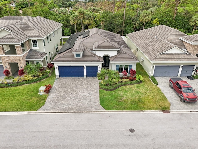 view of front of house featuring solar panels, a garage, and a front lawn