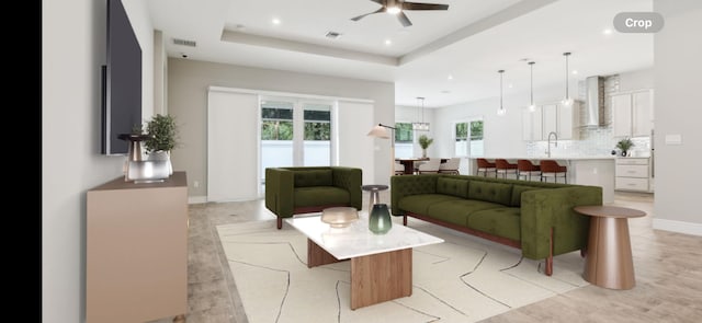 living room featuring ceiling fan and a raised ceiling