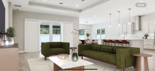 living room featuring a raised ceiling and sink