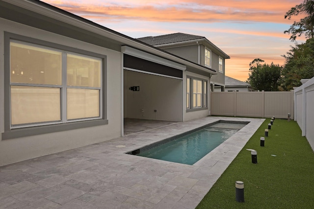 pool at dusk with a patio area