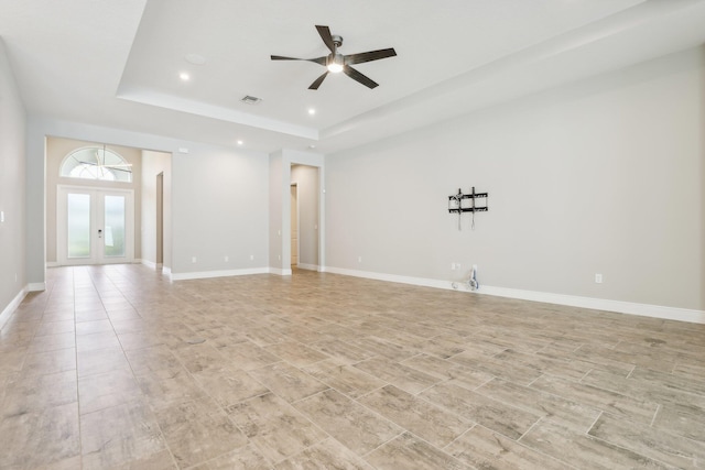 empty room with french doors, a raised ceiling, and ceiling fan