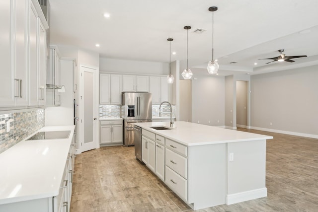 kitchen with a kitchen island with sink, sink, white cabinets, and appliances with stainless steel finishes