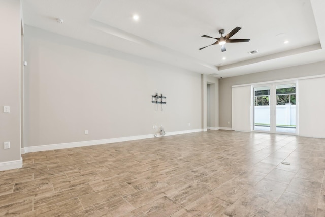 empty room featuring ceiling fan and a raised ceiling