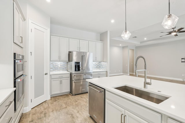 kitchen with white cabinetry, sink, backsplash, decorative light fixtures, and appliances with stainless steel finishes