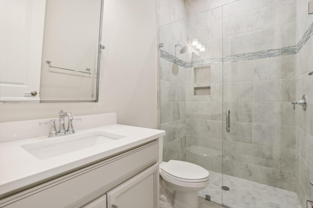 bathroom with a shower with door, vanity, and toilet