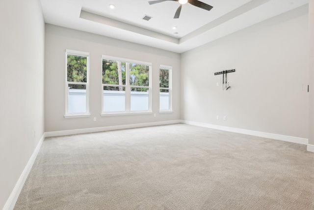 carpeted spare room featuring a raised ceiling and ceiling fan