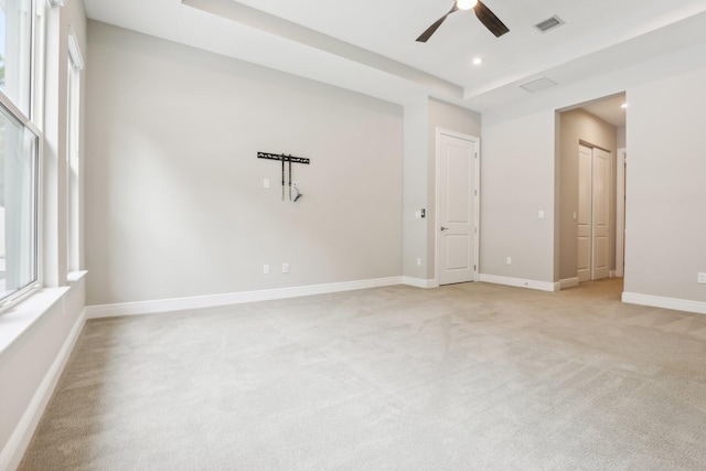 carpeted spare room featuring a wealth of natural light, a raised ceiling, and ceiling fan