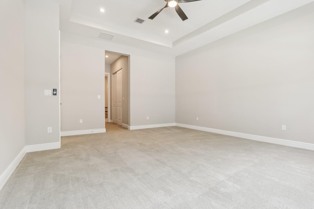 unfurnished room featuring a tray ceiling, ceiling fan, and light colored carpet