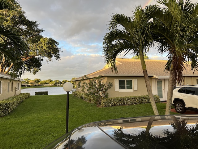 view of home's exterior featuring a yard, a shingled roof, and stucco siding