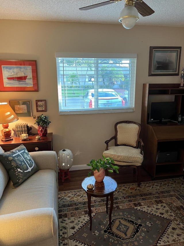 living room featuring dark hardwood / wood-style flooring, a textured ceiling, and ceiling fan