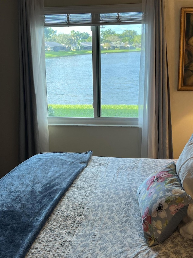 bedroom featuring a water view and multiple windows