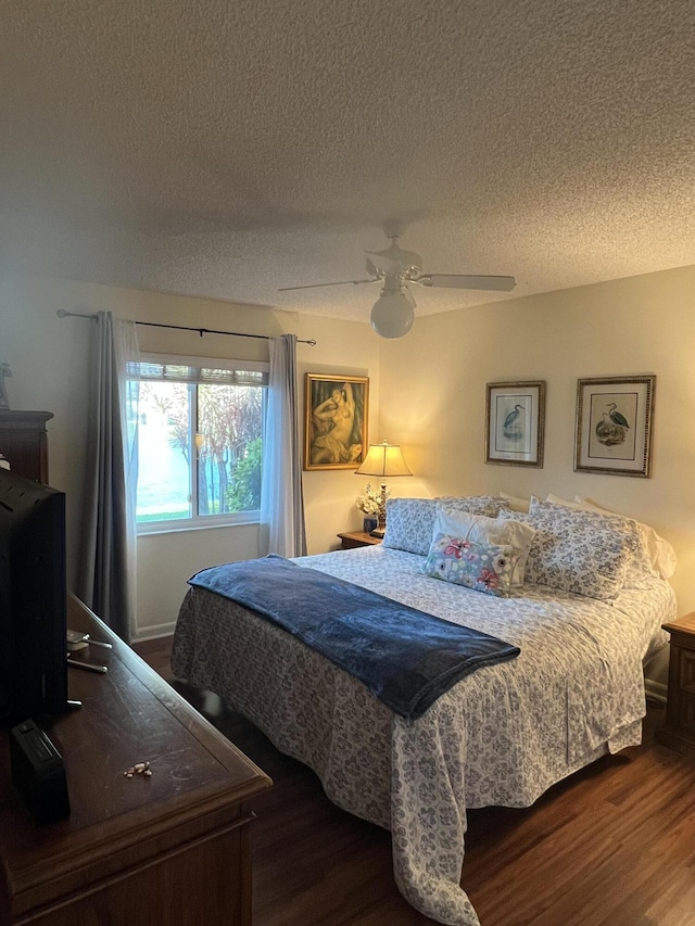 bedroom with ceiling fan, dark hardwood / wood-style floors, and a textured ceiling