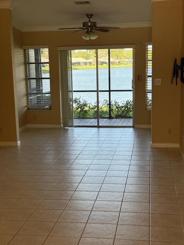 empty room with light tile patterned floors, a water view, ceiling fan, and crown molding