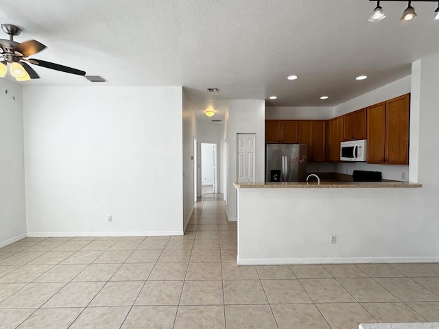 kitchen with hanging light fixtures, kitchen peninsula, stainless steel fridge, a textured ceiling, and light tile patterned floors