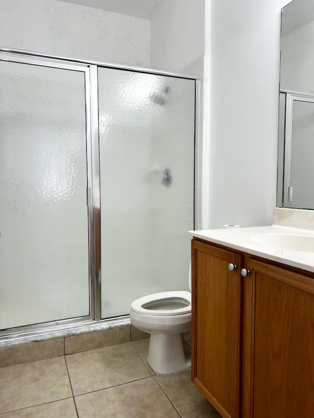 bathroom featuring tile patterned floors, vanity, toilet, and walk in shower